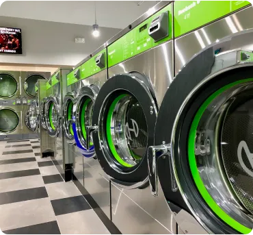 A row of bright and colorful commercial washing machines in various sizes at a clean laundromat.