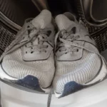 Unrecognizable man washing shoes at industrial laundromat