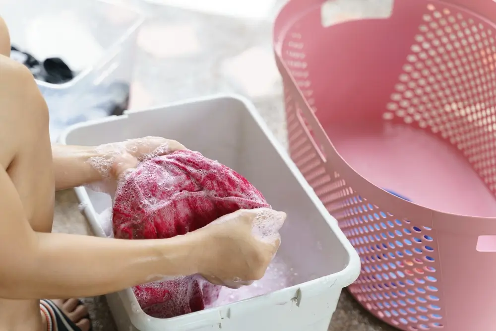 Asian woman washing red cloth with detergent by hands.