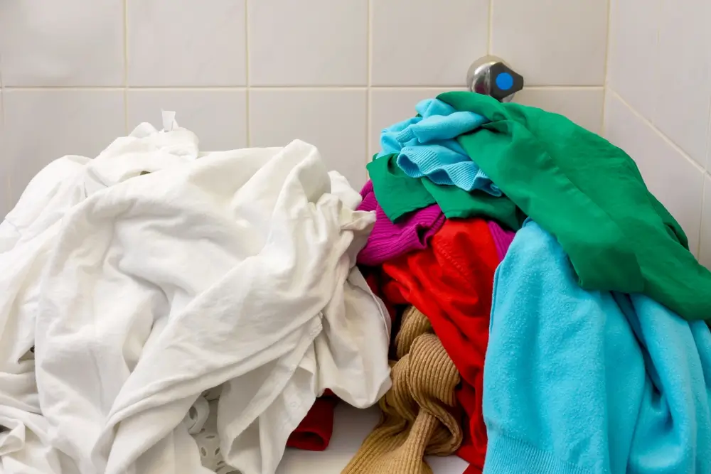 Pile of white and colors clothes being separate before load in to watching machine