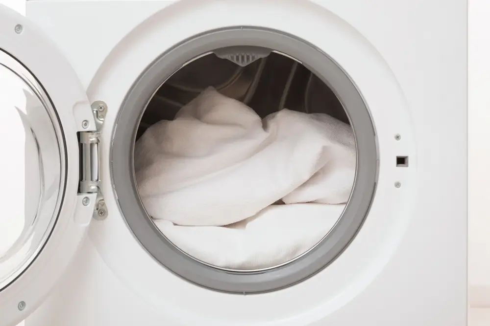 Opened front load washing machine full of white clothes.