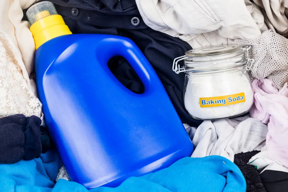 Closeup on baking soda with detergent and pile of dirty laundry