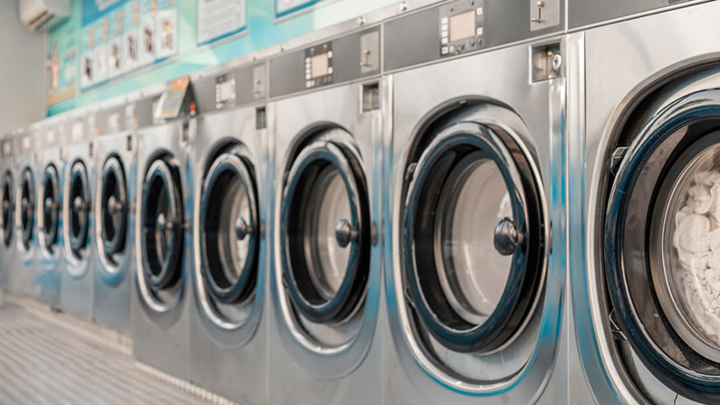 Row of washing machines in public laundry. Commercial cleaning services or utility management in communal spaces. Laundromat. Shared amenities. Self-service, coin laundry, or coin wash.
