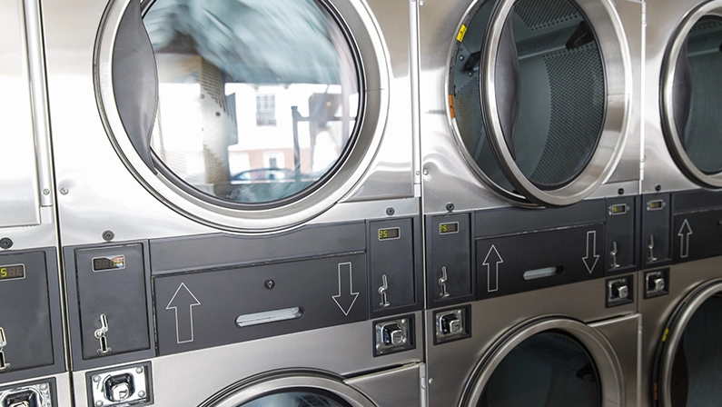 self-service laundry facilities concept - washing machines with clothes inside at laundromat