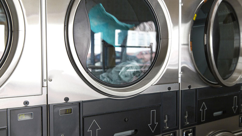 self-service laundry facilities concept - washing machines with clothes inside at laundromat