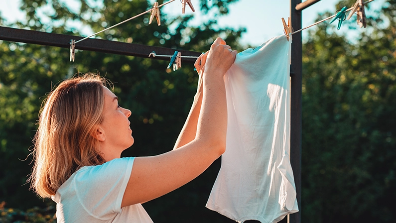 A young caucasian smiling housewife hanging laundry. Vertical. Housework concept.