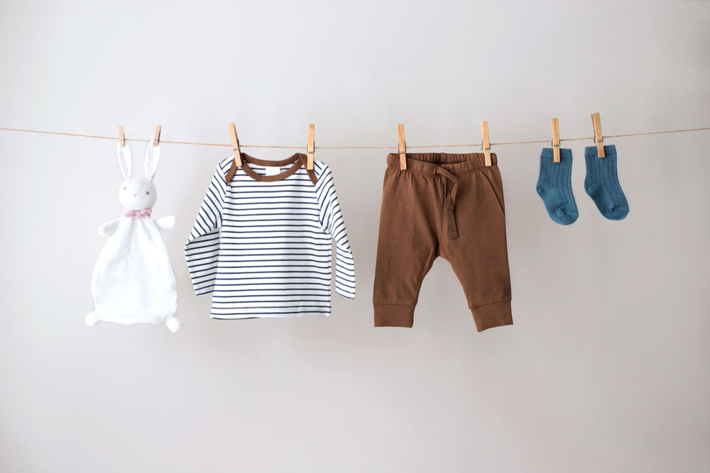 Baby clothes hanging on the rope on gray background.