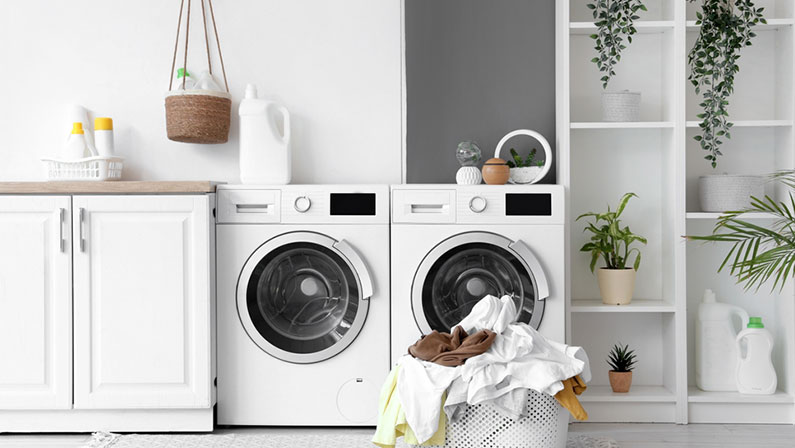 Basket with dirty clothes near washing machines in laundry room
