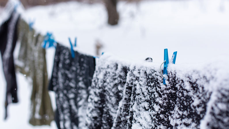 Winter. Clothes are drying on the street. Clothes covered with snow dries on a tightened rope
