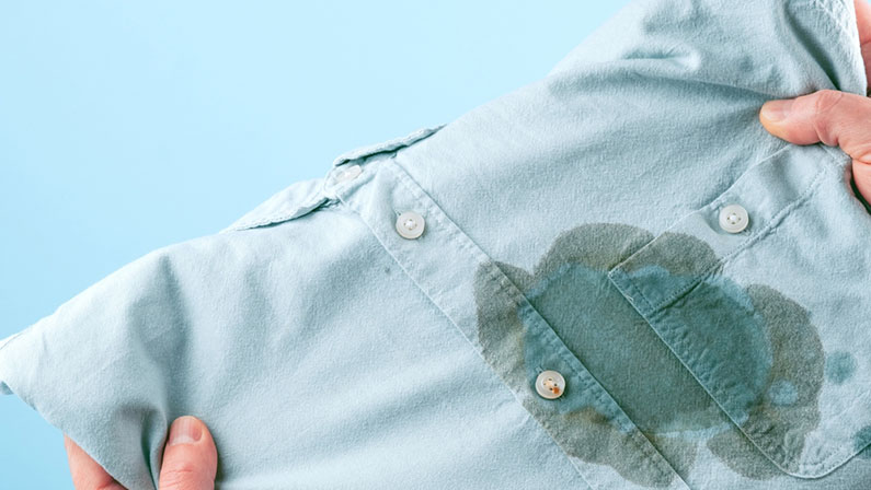 Men hands showing a dirty shirt and visual evaluation of stain on clothes on a blue background. Spoiled linen. isolated. High quality photo