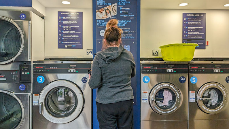 Woman using self-service laundry machines in a public laundromat