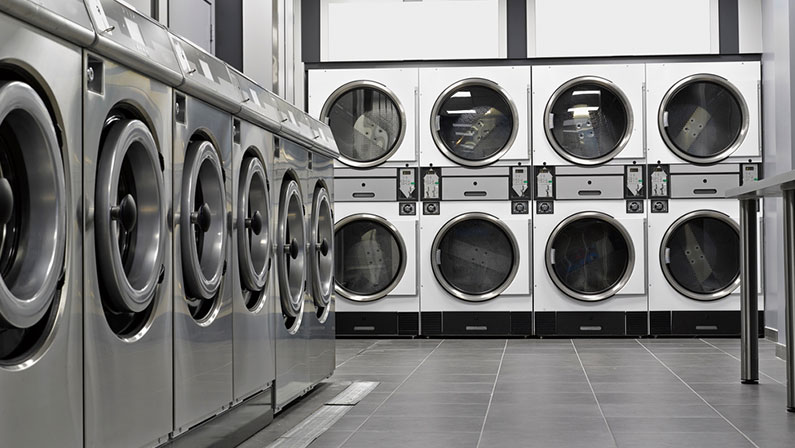 Row of industrial washing machines in a public laundromat
