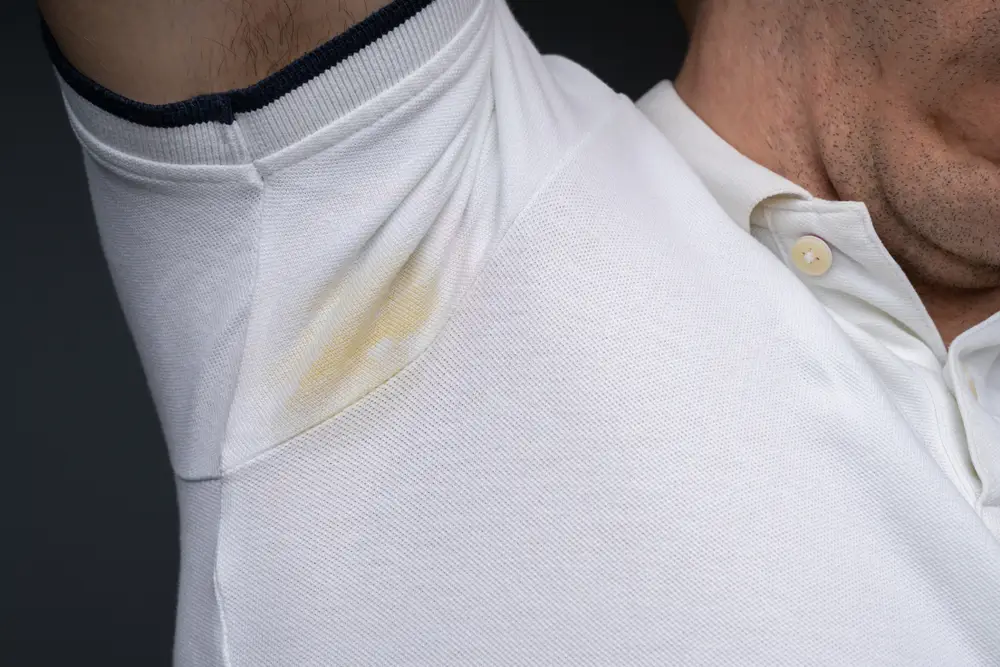 Close-up Of Man's Armpit Sweating Very Badly Against Gray Background
