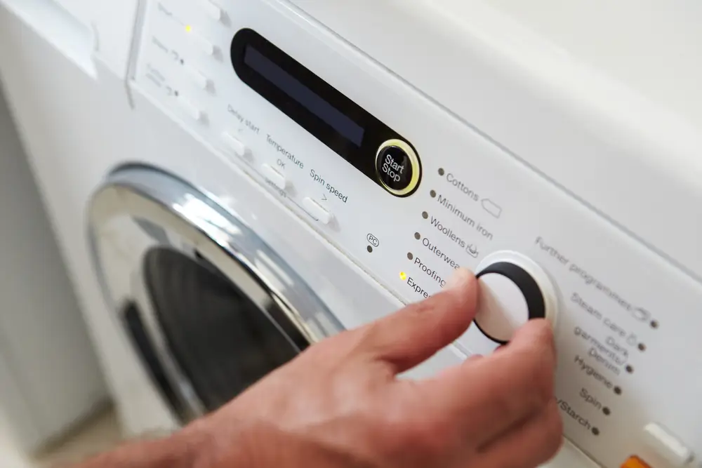 Close Up Of Man Choosing Cycle Program On Washing Machine
