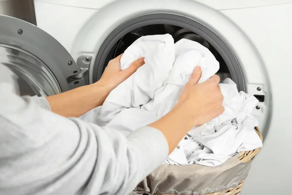 Female hands getting out clean clothes from washing machine
