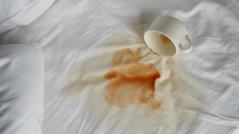 cup of coffee spilled white bed
