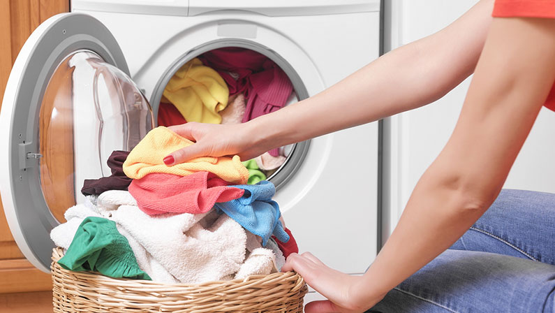 Preparing the wash cycle. Washing machine, hands and clothes.
