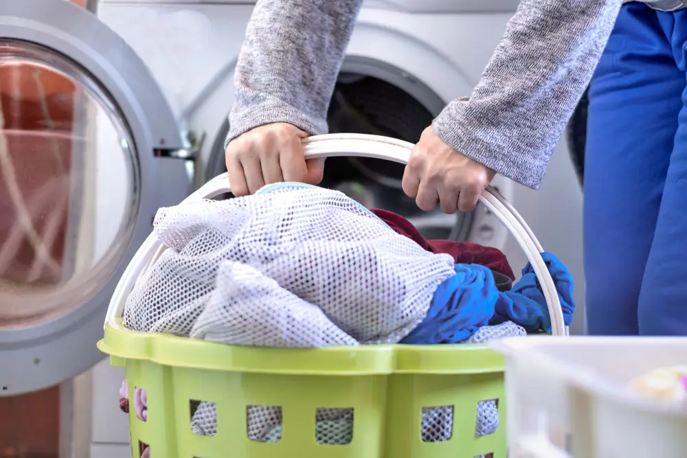 Close up of housewife hand holding basket full of cloths. Woman in laundry.
