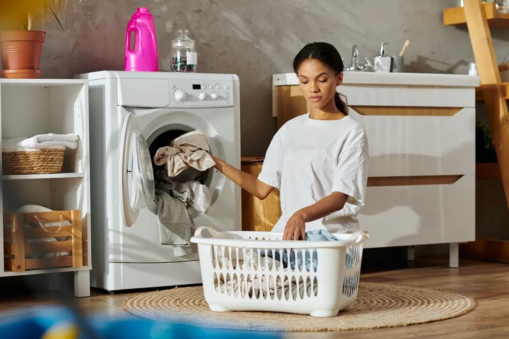 A young African American woman carefully sorts laundry in her stylish apartment space.