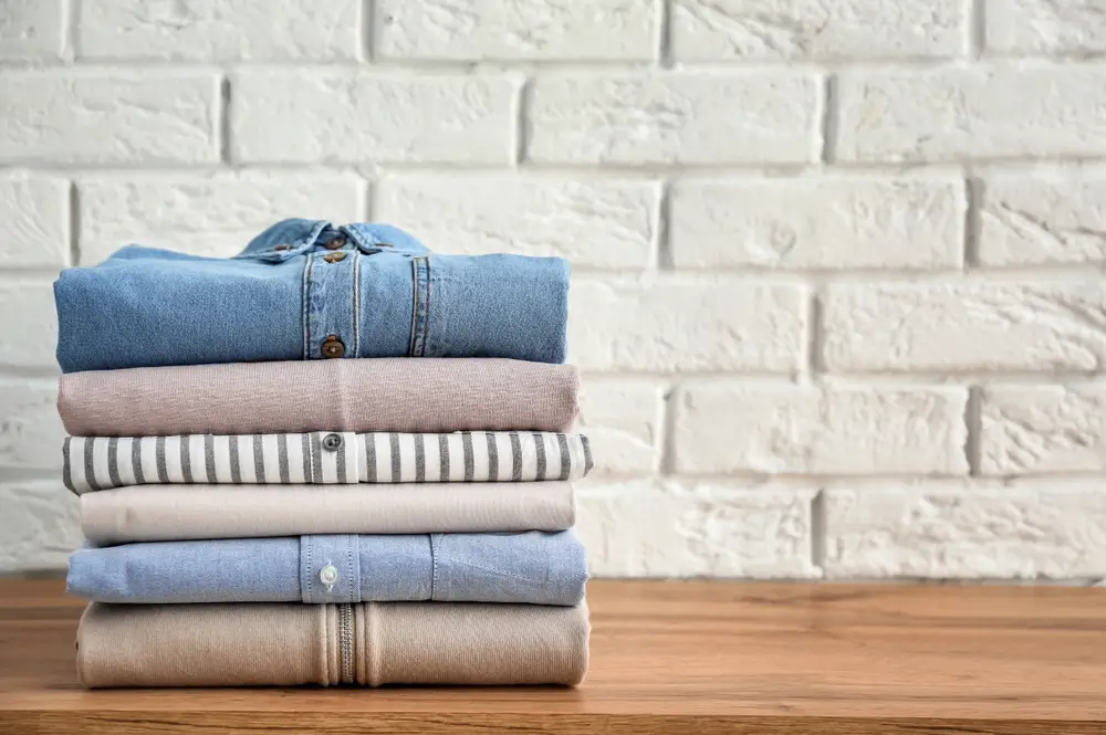 Stack of clothes on table near brick wall