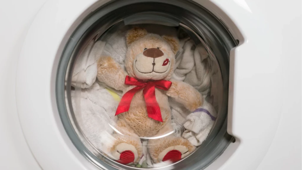 Teddy bear washes in the washing machine.
