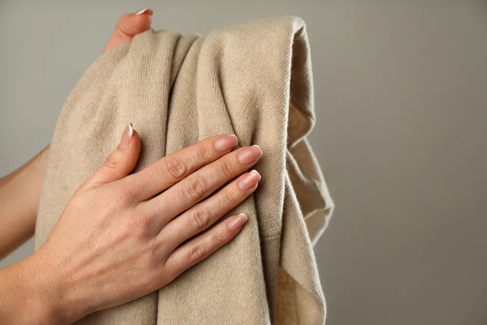 Woman with cashmere sweater on beige background, closeup