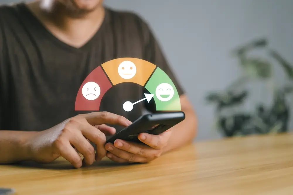man holding phone with a sad, neutral, and happy faces concept for using ratings