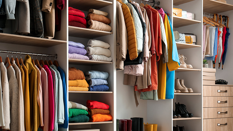 Rack with stylish female autumn clothes in modern wardrobe