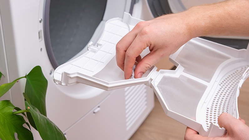A man takes a lint filter out of the dryer and cleans it from dust, lint, hair, wool.
