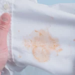 Man's handing hold clothes with a stain from tomato sauce. top view