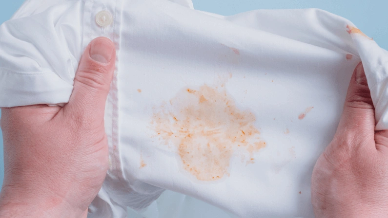Man's handing hold clothes with a stain from tomato sauce. top view