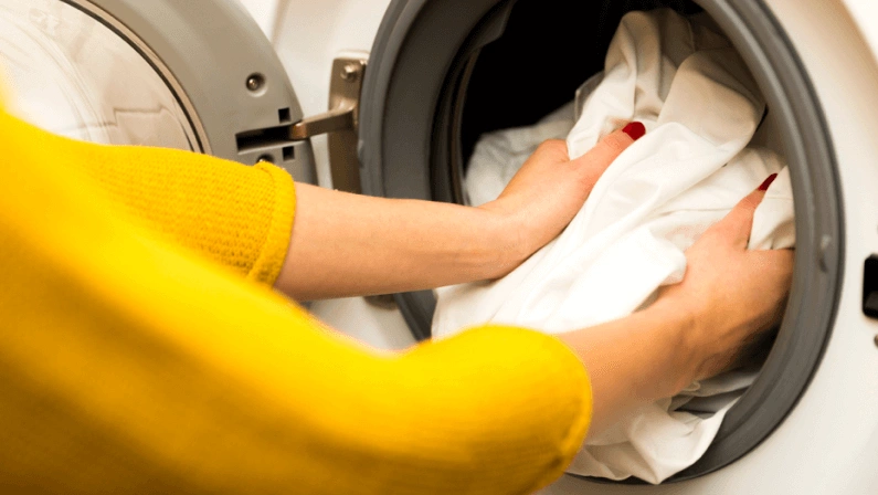 Woman hand loading dirty clothes in washing machine