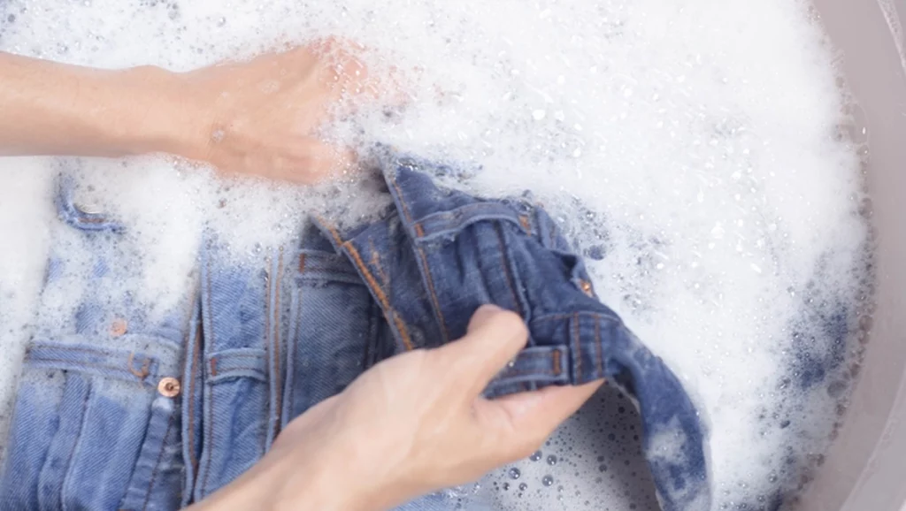 Washing jeans, young woman's hand washing jeans, close-up