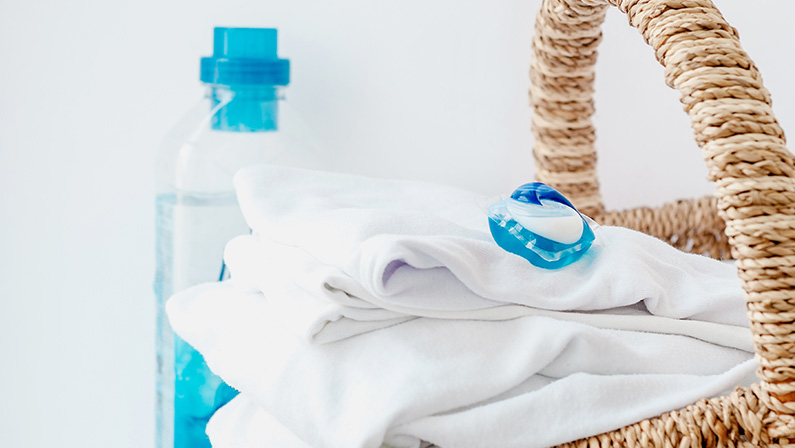 Stack of clothes and laundry pods on table at home