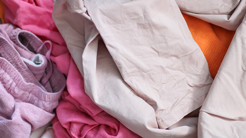 A pile of colorful laundry. Women's clothes in different shades of pink. All clothes made of natural fibers: cotton, viscose, thin wool.