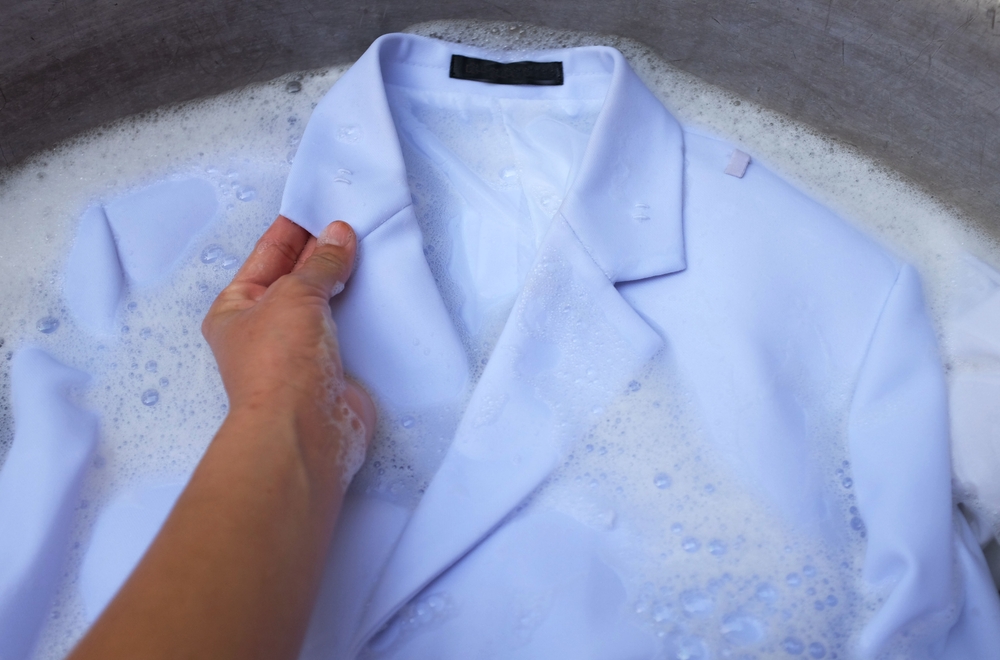 Hand of Asian housewife washing white clothes ,Dirty shirt collar ,White shirt, white suit,Student uniforms with bubble detergent in basin