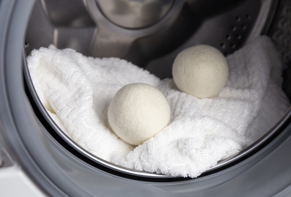 Using wool dryer balls for more soft clothes while tumble drying in washing machine concept