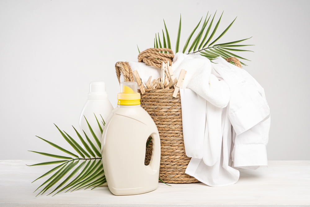 Wicker basket with white linen, clothespins, clothesline, washing gel and fabric softener