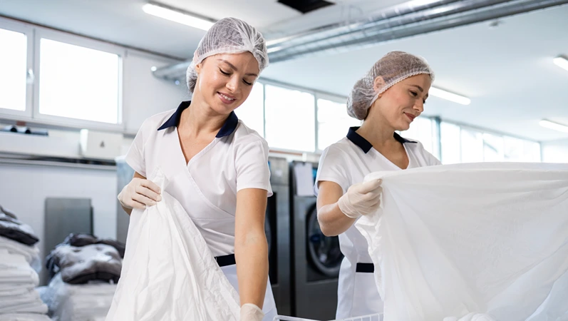 Hospital hygiene workers sorting dirty laundry and preparing for washing.