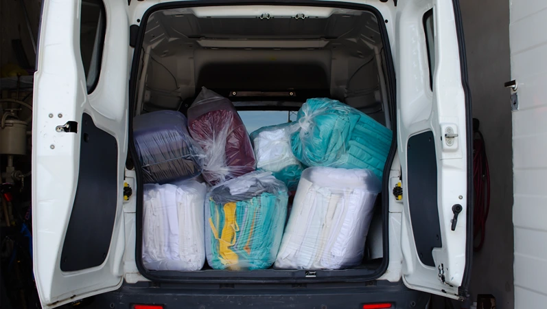 Utility vehicle loaded with clean clothes bags for delivery. Industrial laundry service for hospitals and clinics. Business concept.