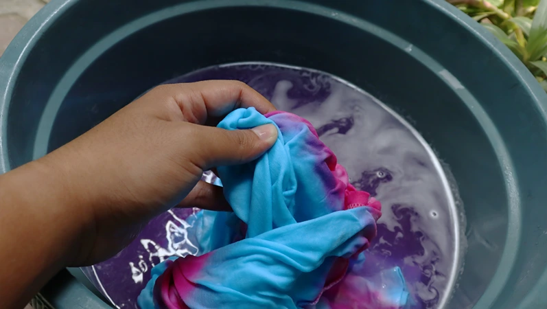Close up of colorful clothes in a wash basin with liquid detergent, tie dye making process, selective focus