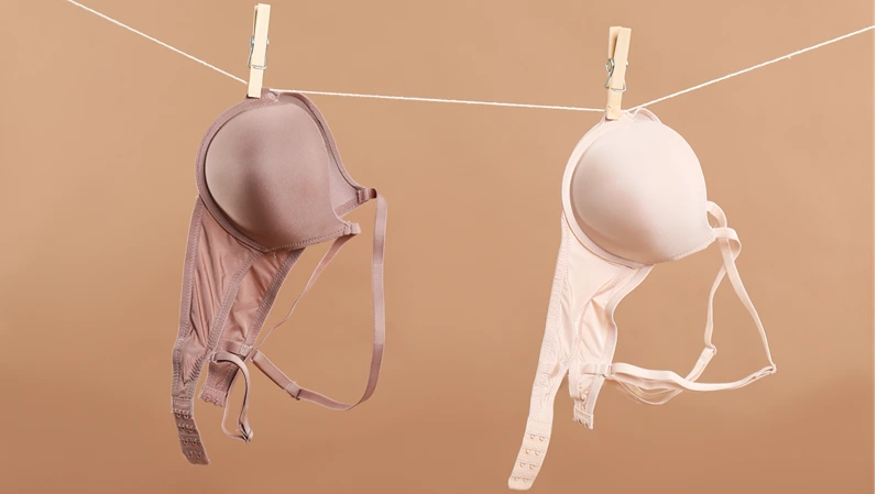 Beautiful bras hanging on rope against dark beige background