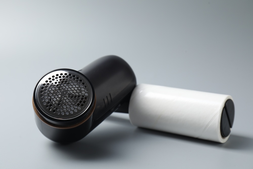 Lint roller and fabric shaver on light grey background, closeup